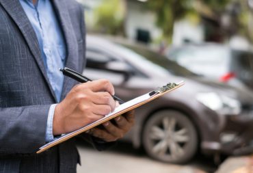 insurance-adjuster-examining-vehicle-damages-suburban-street Dah Cheong Insurance Claim cover
